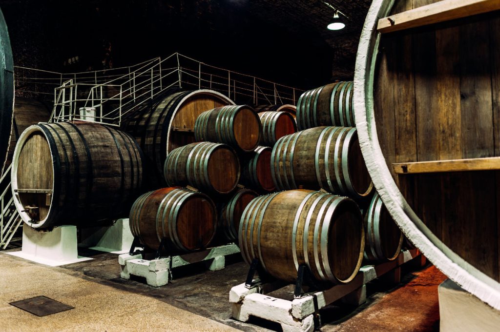 Old barrels in the wine cellar. Wine cellar with old oak barrels, production of fortified dry or semi-sweet wine. The wine barrels are stored in the old cellar of the winery. Brewery, winery